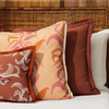 Three pillows with floral patterns placed on a bed with white bedding