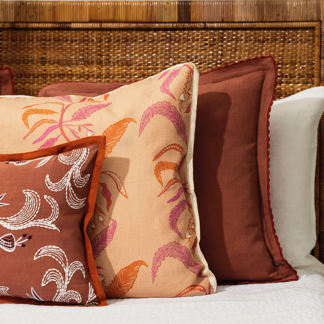 Three pillows with floral patterns placed on a bed with white bedding