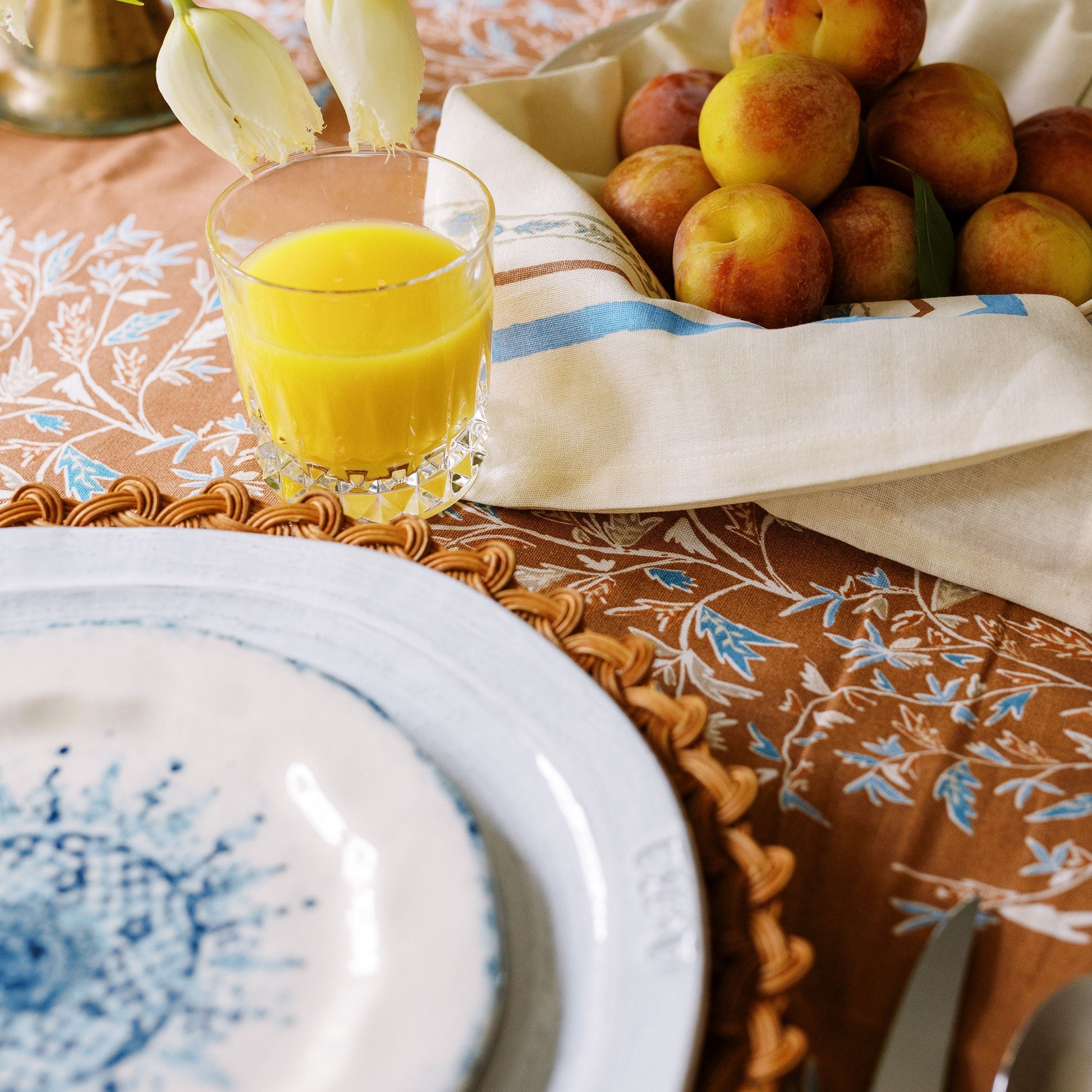holly vine terracotta tablecloth styled with a fruit basket and glass of orange juice