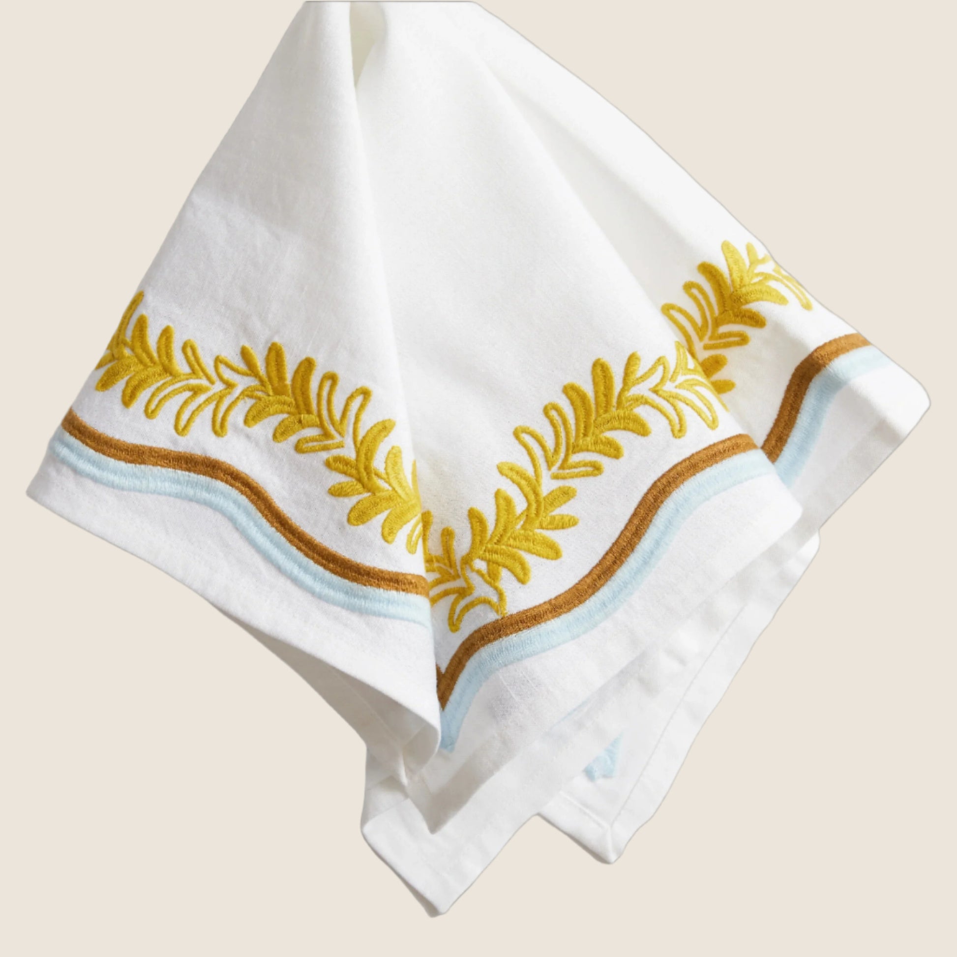 white napkin with gold leaft pattern and brown and blue trim