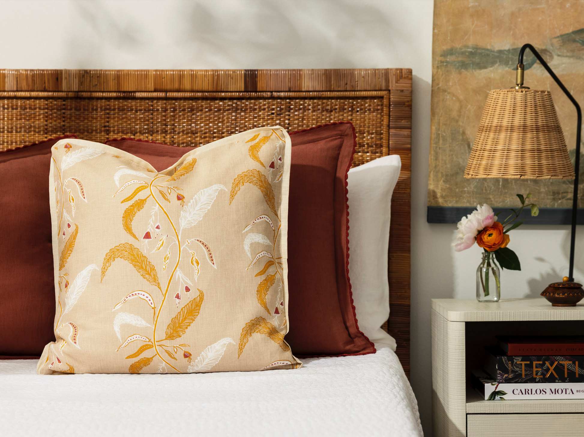 tuileries citrine pillow on a bed with white bed linen and night stand with bud vases