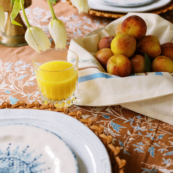 holly vine terracotta tablecloth styled with a fruit basket and glass of orange juice