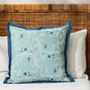 marseille cobalt pillow styled on a bed with white linens against a can headboard