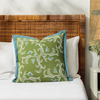 marseille verdant pillow placed on a bed with white bed linen and cane bedhead