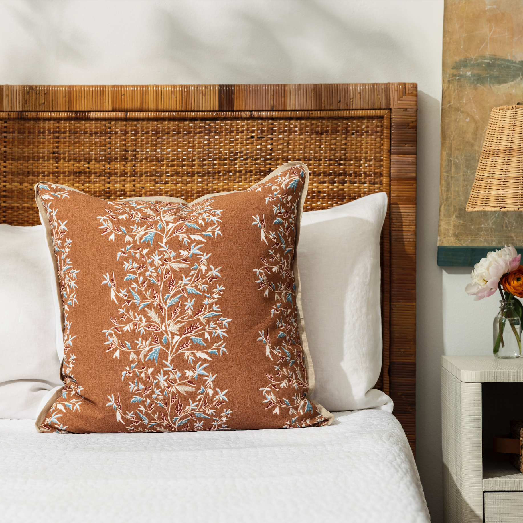 holly vine terracotta pillow styled on a bed with white bed linen